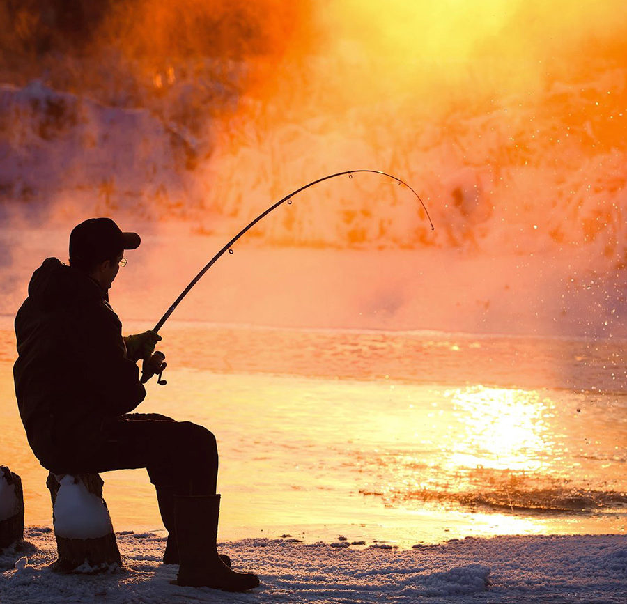 Man ice fishing at sunset